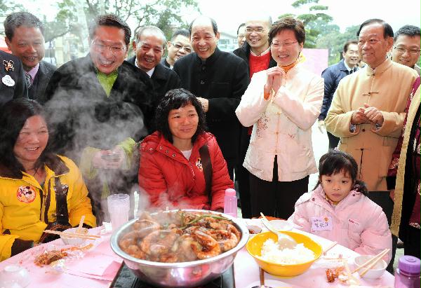 發展局局長林鄭月娥在大埔林村與正在品嚐盆菜的的小朋友及其家人共慶新春。